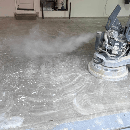 grinder working on residential garage concrete floor coatings