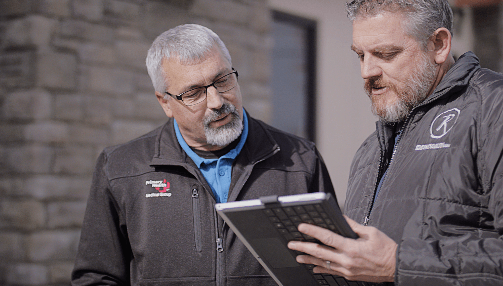 Roe Paint estimator talking to a business owner about a painting or concrete coatings project on an ipad